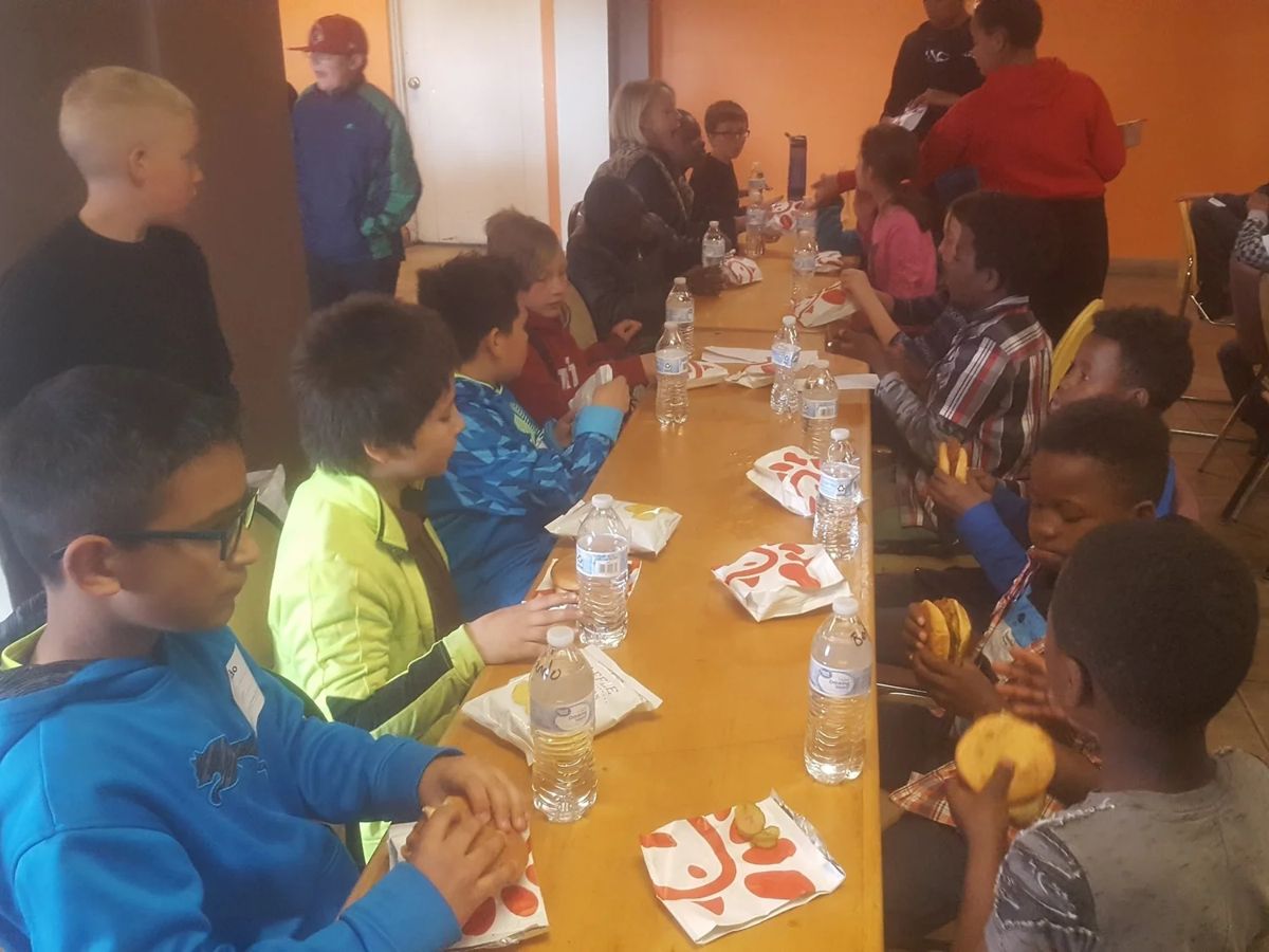 Kids eating lunch together at a long table during day camp