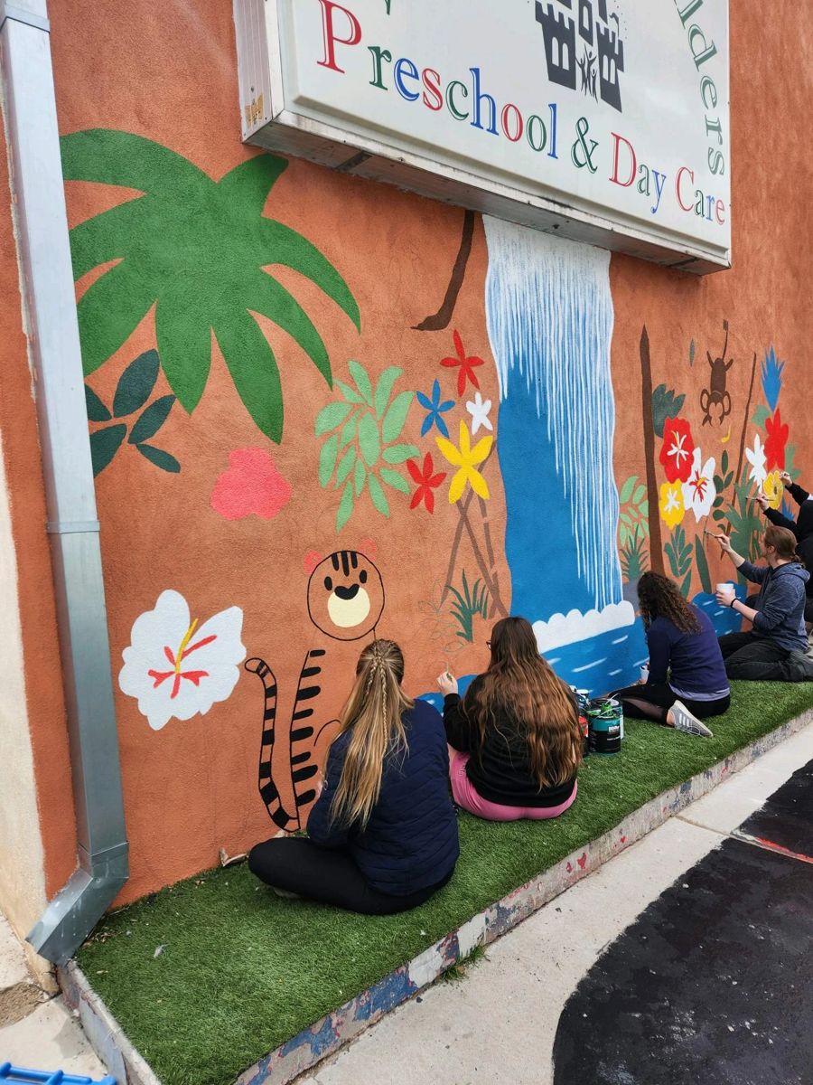 Children sitting in front of the painted Kingdom Builders Preschool and Day Care mural