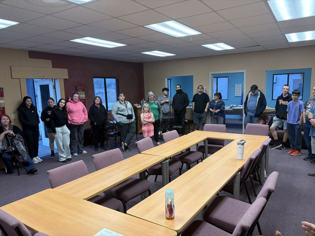 A group of adult students standing around a classroom table at the Mission Training Center